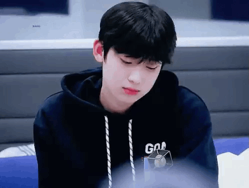 A Young Boy Wearing A Black Hoodie Is Sitting On A Couch . GIF