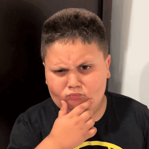 A Young Boy Wearing A Black Shirt With A Yellow Batman Logo On It GIF