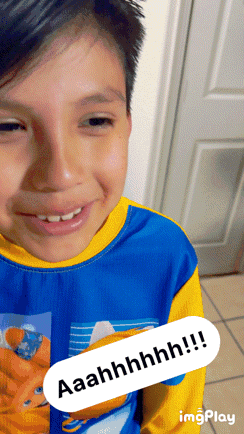 a young boy wearing a blue and yellow shirt is smiling with the words aaahhhhh !!! visible