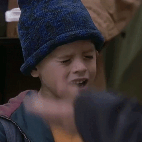 A Young Boy Wearing A Blue Hat And A Jacket GIF