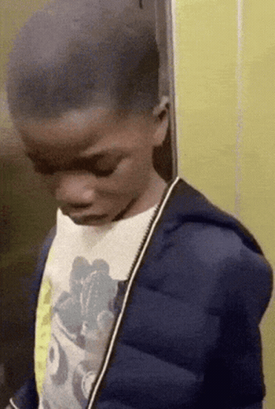 A Young Boy Wearing A Blue Jacket And A Mickey Mouse Shirt GIF
