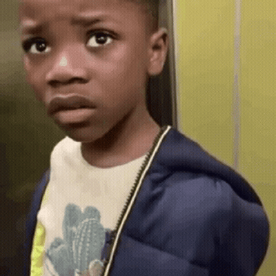 A Young Boy Wearing A Blue Jacket And A White Shirt Is Making A Funny Face . GIF