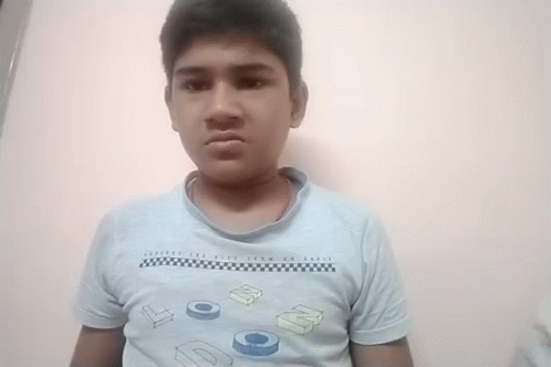 A Young Boy Wearing A Blue Shirt With The Letters Dc On It Makes A Funny Face GIF