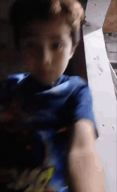 A Young Boy Wearing A Blue Shirt With The Word Spiderman On It Is Looking At The Camera . GIF