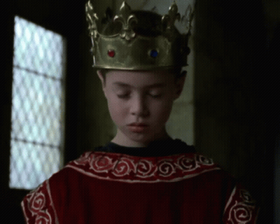A Young Boy Wearing A Gold Crown And A Red Dress GIF