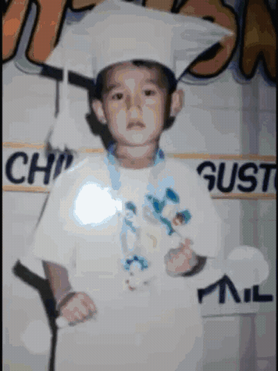 A Young Boy Wearing A Graduation Cap And Gown Poses For A Photo GIF