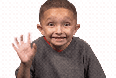 A Young Boy Wearing A Gray Shirt Is Waving His Hand GIF