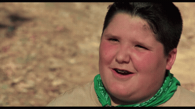 A Young Boy Wearing A Green Bandana And Braces Smiles GIF