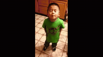 A Young Boy Wearing A Green Shirt Is Standing On A Tiled Floor . GIF