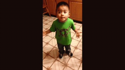 A Young Boy Wearing A Green Shirt Is Standing On A Tiled Floor . GIF