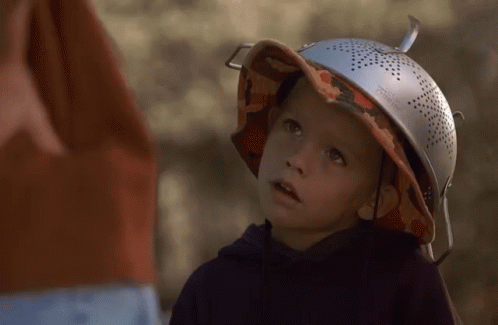 A Young Boy Wearing A Hat And A Strainer On Top Of His Head GIF