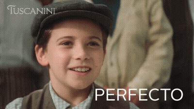 A Young Boy Wearing A Hat Is Smiling In Front Of A Tuscanini Ad GIF