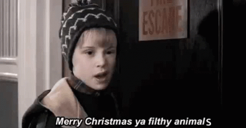 A Young Boy Wearing A Hat Is Standing In Front Of A Door . GIF