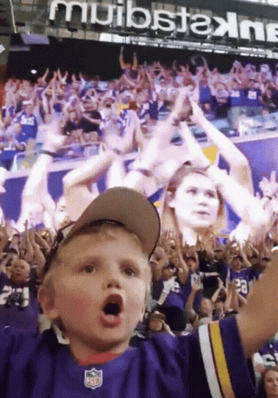 A Young Boy Wearing A Nfl Jersey Stands In A Crowd GIF