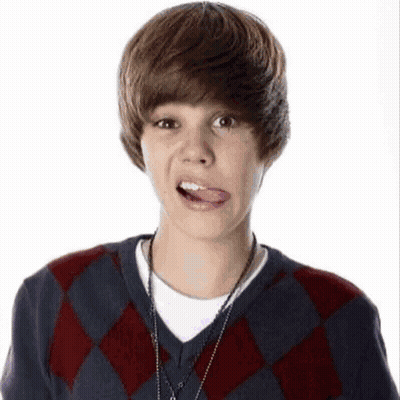 A Young Boy Wearing A Plaid Sweater Is Sticking Out His Tongue . GIF