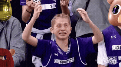 A Young Boy Wearing A Purple Northwestern Jersey Is Crying While Sitting In A Crowd . GIF