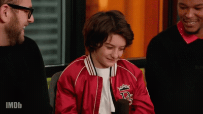 A Young Boy Wearing A Red Jacket With A Crown On It Is Talking Into A Microphone . GIF