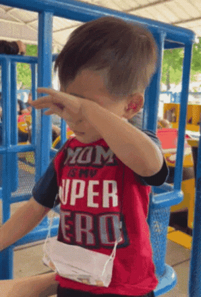 A Young Boy Wearing A Red Shirt That Says " Mom Is My Super Hero " GIF