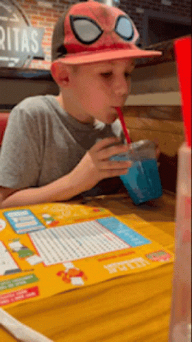 A Young Boy Wearing A Spider Man Hat Drinks A Drink Through A Straw GIF