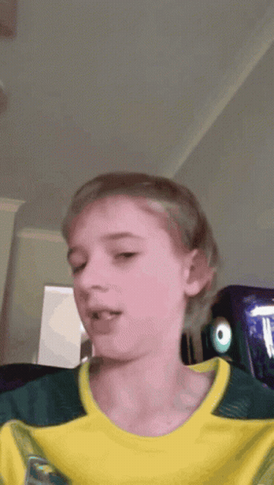 A Young Boy Wearing A Yellow And Green Shirt With The Letter T On It GIF