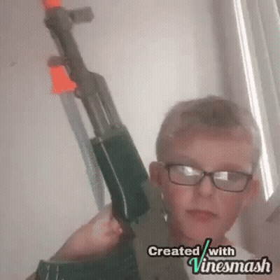 A Young Boy Wearing Glasses Is Holding A Toy Gun In His Hands . GIF