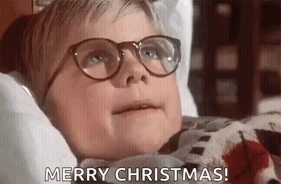 A Young Boy Wearing Glasses Is Laying On A Bed And Saying Merry Christmas . GIF