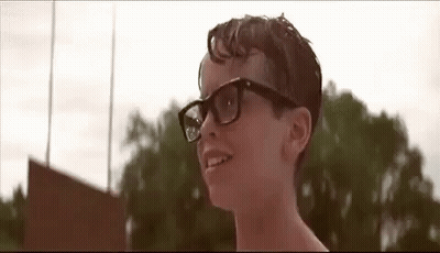 A Young Boy Wearing Glasses Is Smiling In Front Of A Field . GIF