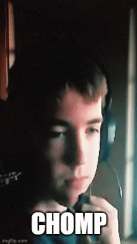 A Young Boy Wearing Headphones And A Microphone Is Making A Funny Face And Saying Chomp . GIF