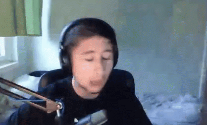 A Young Boy Wearing Headphones And A Microphone Is Making A Funny Face . GIF