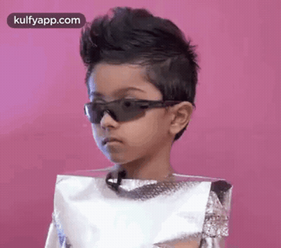 A Young Boy Wearing Sunglasses And A Foil Bag On His Head . GIF