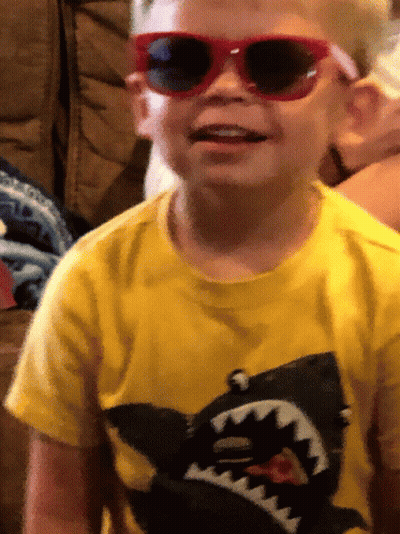 A Young Boy Wearing Sunglasses And A Yellow Shirt With A Picture Of A Shark On It GIF