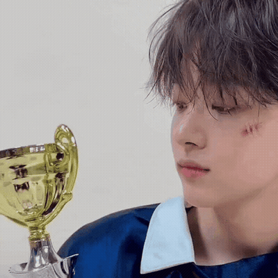 A Young Boy With A Trophy In His Hand Has A Scratch On His Face . GIF