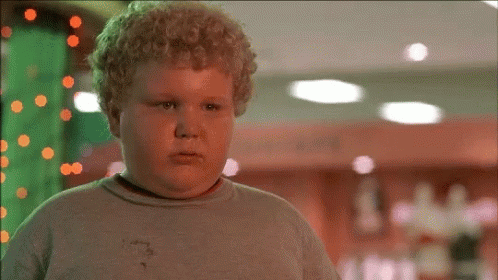 A Young Boy With Curly Hair Is Standing In A Room GIF