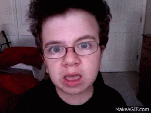 A Young Boy With Glasses Is Making A Funny Face . GIF