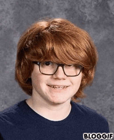 A Young Boy With Red Hair And Glasses Is Smiling For A Picture . GIF
