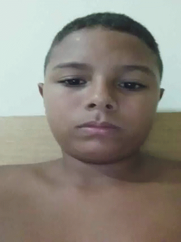 A Young Boy Without A Shirt Is Looking At The Camera With A Serious Look On His Face . GIF