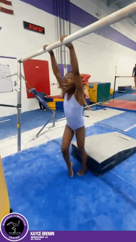 A Young Girl Hangs From A Bar In A Gym With Kayce Brown Written On The Bottom GIF