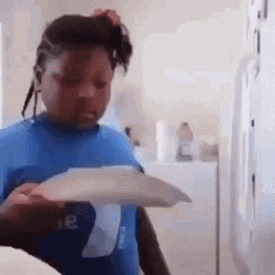 A Young Girl In A Blue Shirt Is Holding A Piece Of Paper In Her Hand . GIF