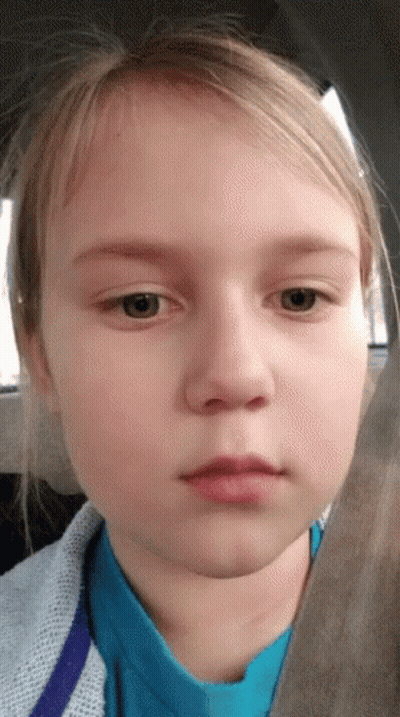 A Young Girl In A Blue Shirt Looks At The Camera With A Serious Look On Her Face GIF