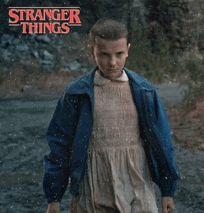 A Young Girl In A Dress And Blue Jacket Is Standing In The Rain . GIF