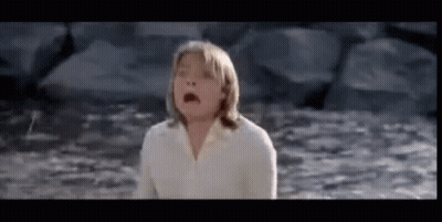 A Young Girl In A White Shirt Is Standing In The Water . GIF