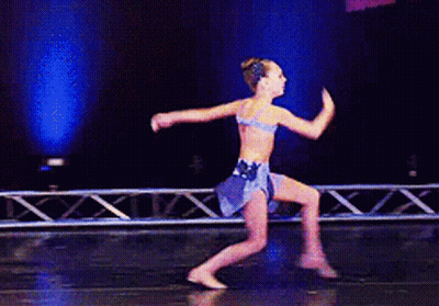 A Young Girl Is Dancing On A Stage In A Blue Dress GIF