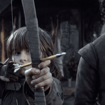 A Young Girl Is Holding A Bow And Arrow In Her Hands GIF