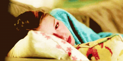 A Young Girl Is Laying On A Bed With A Blue Blanket On Her Head . GIF