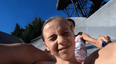 A Young Girl Is Making A Funny Face While Riding A Water Slide GIF