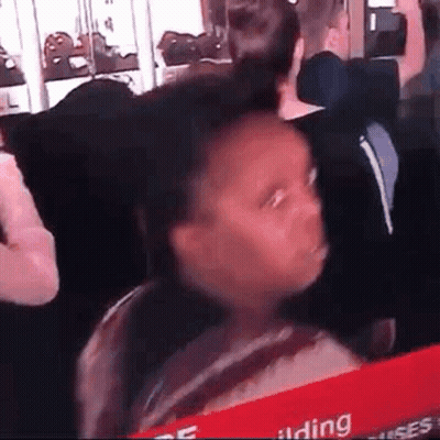A Young Girl Is Making A Funny Face While Sitting In A Crowd Of People . GIF