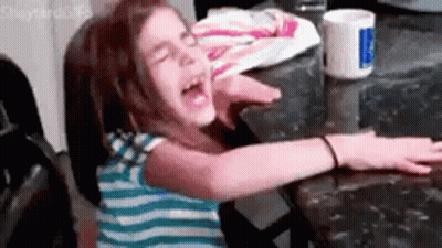 A Young Girl Is Sitting At A Table With Her Arms Outstretched . GIF