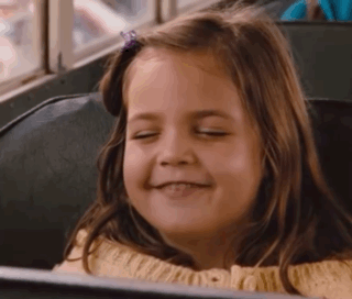 A Young Girl Is Smiling While Sitting On A Bus . GIF