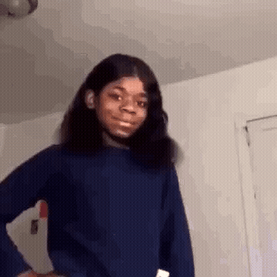 A Young Girl Is Standing In A Room With Her Hands On Her Hips And Making A Funny Face . GIF