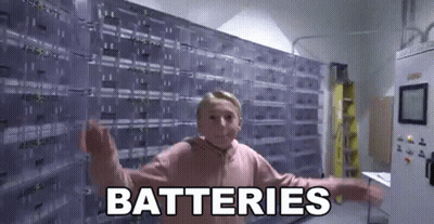 A Young Girl Is Standing In Front Of A Wall Of Batteries And Saying `` Batteries '' . GIF